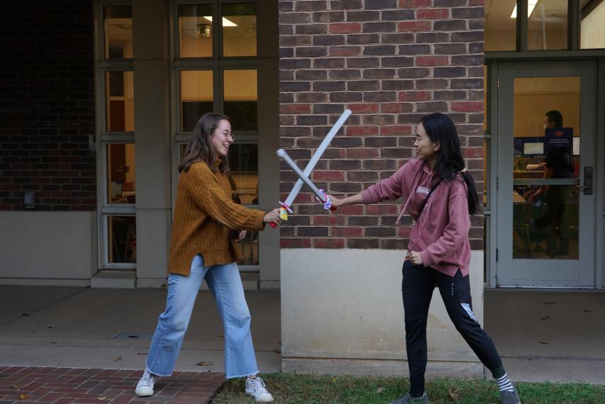 Two girls playing sword-fighting game